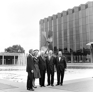 Four men and one woman lined up in front of the fountain in front of the Law School building.