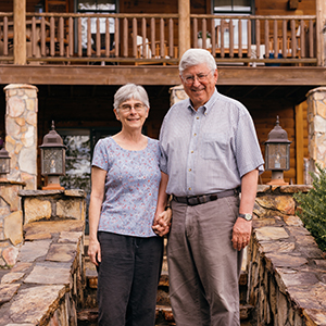 Chris and Pat hold hands in front of a home in 2023