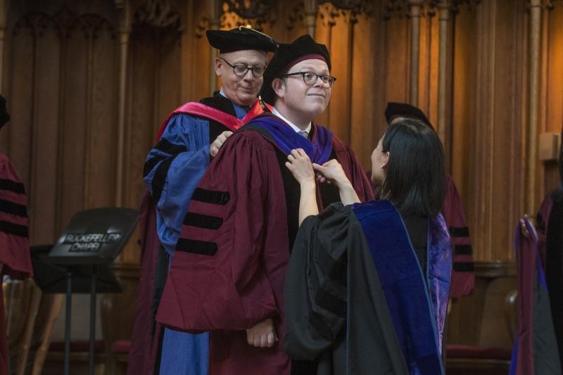 Mateo Aceves is hooded by Professor Levmore and Professor Nou.