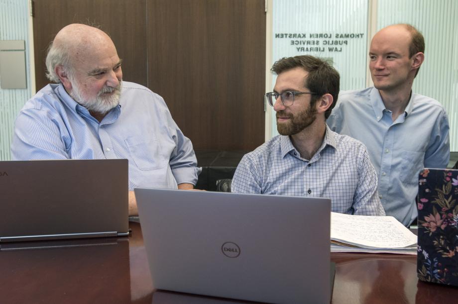 Schmidt talks to students at a table with laptops open in front of them.