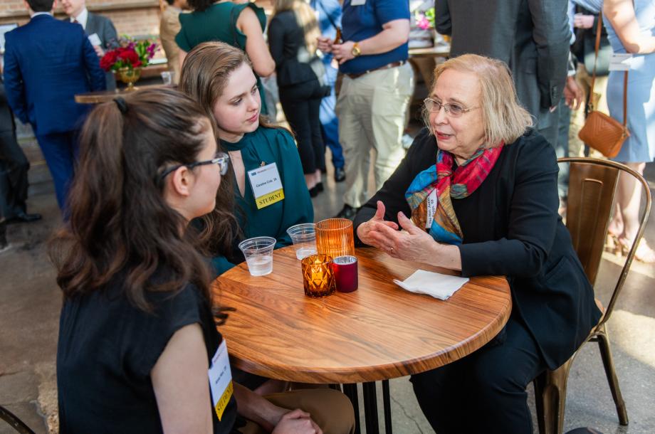 Three women sitting at a round table speaking to each other.