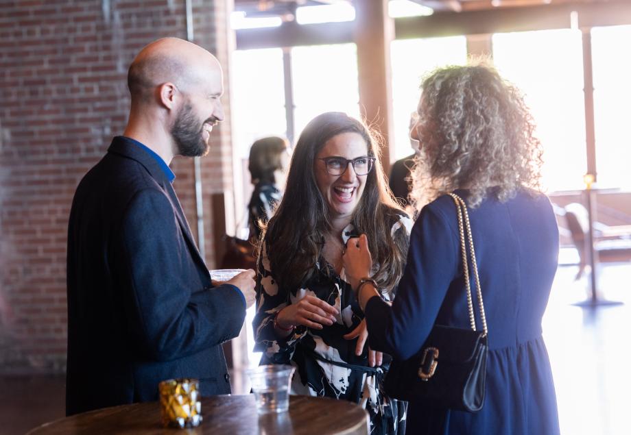 A man and two women standing and talking to each other.