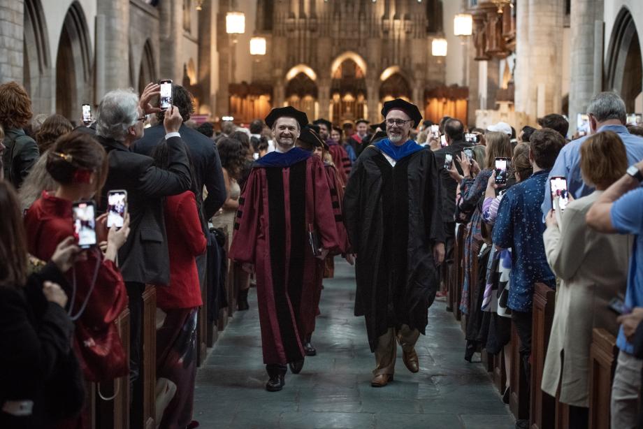 Thomas Miles and Tom Ginsburg lead two rows down the aisle of the chapel.