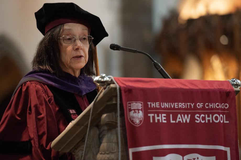 Diane Wood in cap and gown at podium at graduation ceremony.