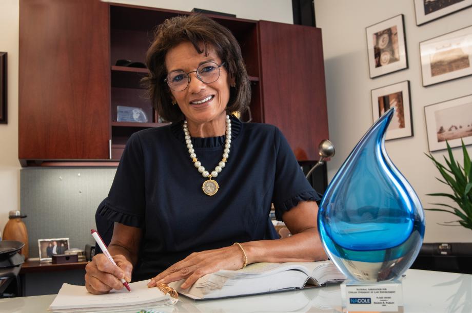 Woman sitting at desk and smiling while looking at the camera. 