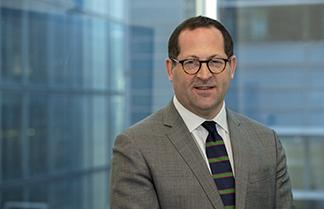 Michael Strauss standing in front of a blue modern glass background 