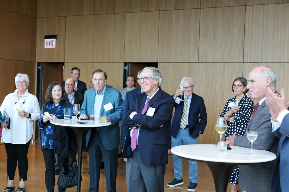 A group of people standing at high boy tables smiling.