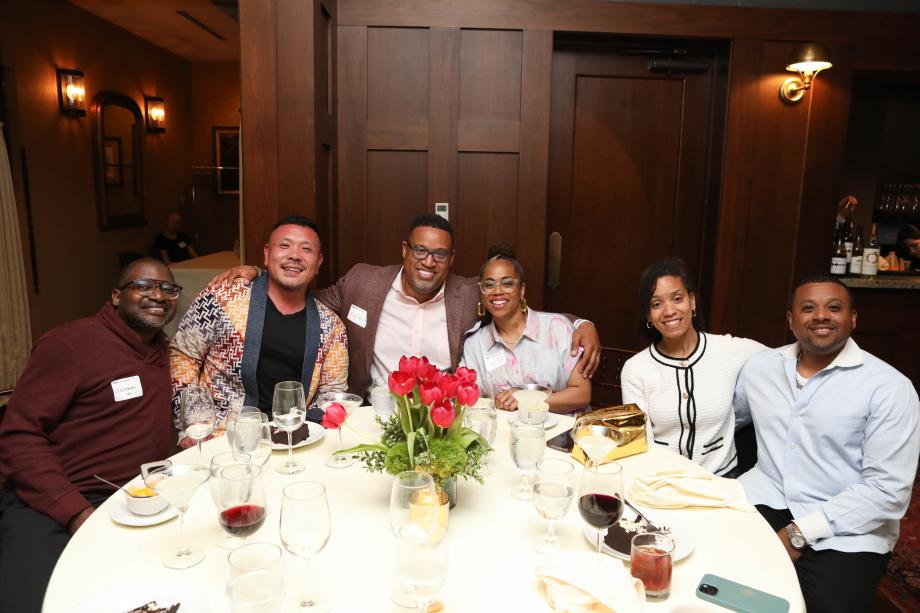 A group of people sitting at a round table smiling at the camera.