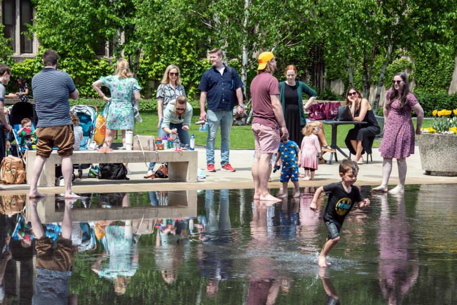 Children and parents wading in a shallow pool on a sunny day.