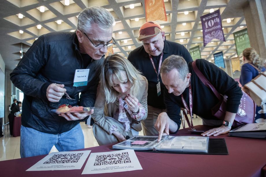 Three men and one woman looking through a binder of photographs.