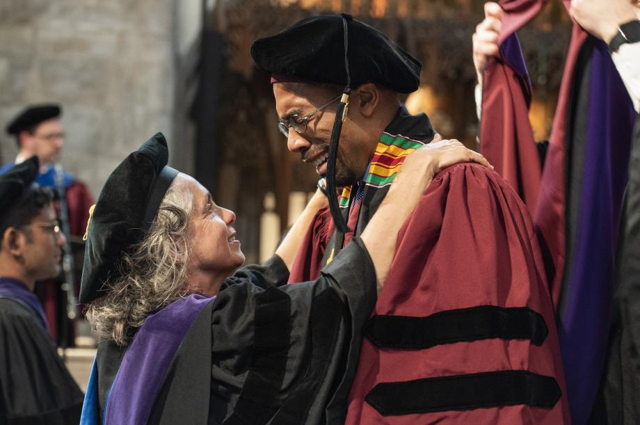 Buss shares a moment with Andre Washington, ’19, as Masur prepares to present his hood.