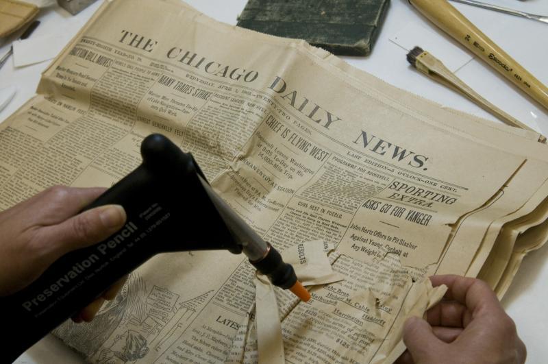 The 1903 box contained many newspapers, now 106 years old, showing the activities surrounding the laying of the cornerstone of the Law School's first long-term home, Stuart Hall. President Teddy Roosevelt attended the event, so it was on the front page of most papers. The papers had varying degrees of damage, and Ann worked to flatten and repair the newspapers.