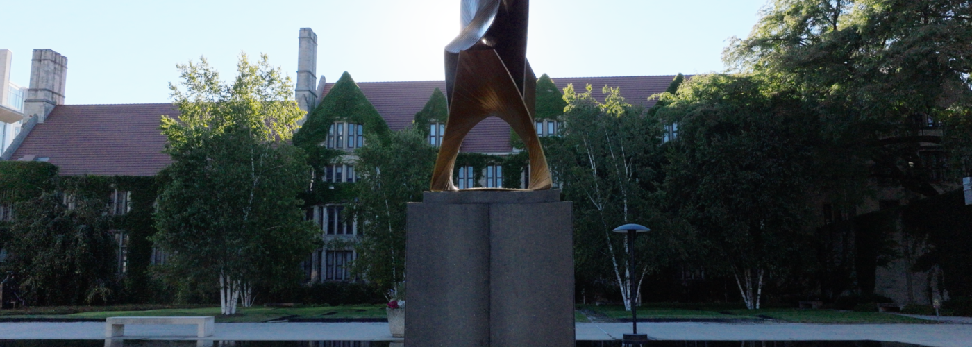 The “Construction in Space in the Third and Fourth Dimension” statue by Antoine Pevsner sits in the Law School's reflecting pool with the sun behind it.