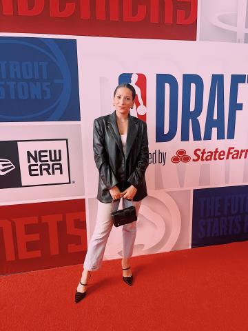 Ally Swartzberg on a red carpet in front of an NBA backdrop.