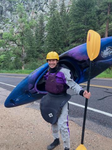 Adrianne Kehne holds a kayak and paddle.