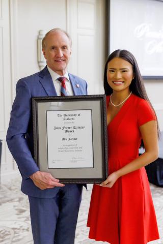 Mae Farmer holds the Ramsey Award with a white man in a suit and tie.