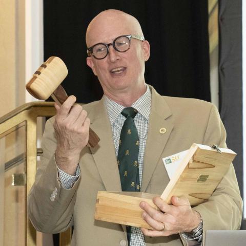 M. Todd Henderson holding wooden gavel