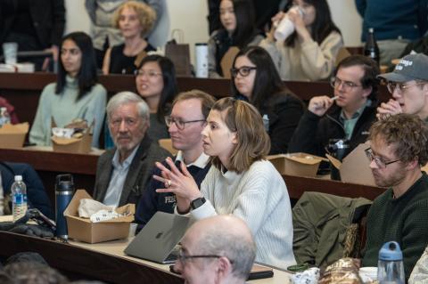 People sitting in a classroom listening to a speaker who is not pictured.