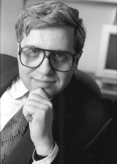 Black and white photograph of Daniel Fischel in a suit and tie with large-rimmed glasses..