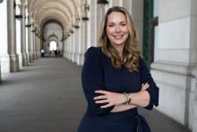 Vanessa Countryman wears a blue dress and pearls, with her arms folded in Washington, DC's Union Station