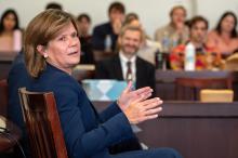 Woman sitting in a chair and speaking to a room full of people