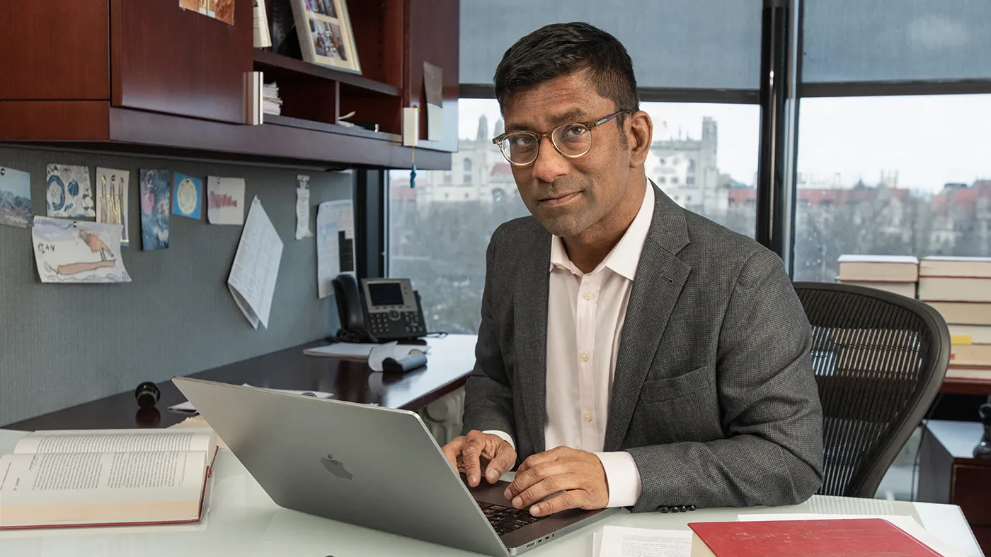 Aziz Huq sitting in his office with his laptop in front of him.